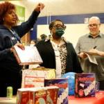 Three adults stand in a school classroom during the math carnival.